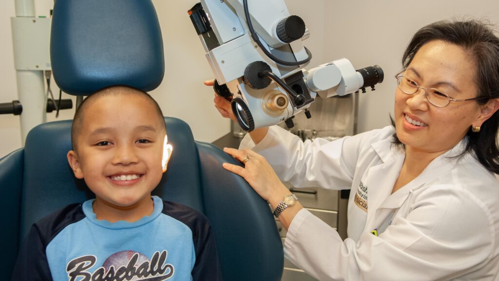 Photo of Dr. Lieu performing an otoscopic exam on young patient