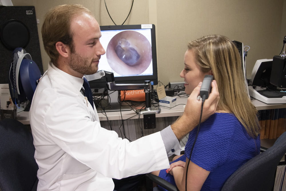 Audiology student examines ear of a patient